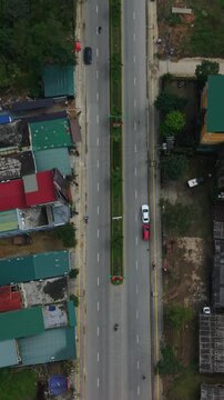 Aerial View Suburban Highway Flanked By Colorful Roofs Phong Nha Vietnam, Asian Pedestrians And Scattered Vehicles, Residential Blocks, Green Patches, Quiet Neighborhood Flow