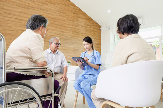 Healthcare professional attentively examines elderly patient alongside two older men within welcoming, modern nursing home environment featuring wood walls and comfortable furnishings.