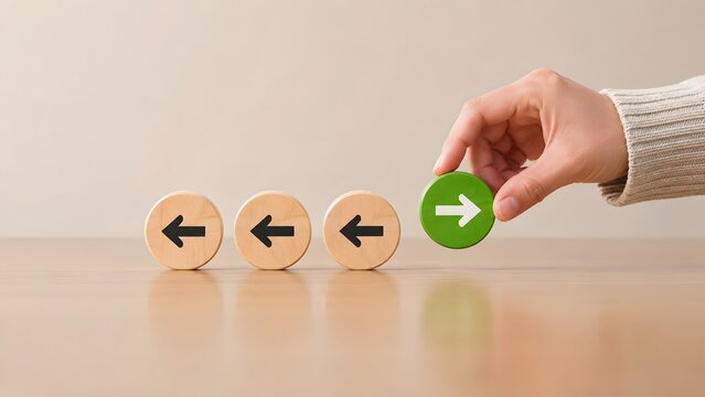 Hand selecting green wooden block with forward arrow among backward arrows symbolizing change of direction and leadership