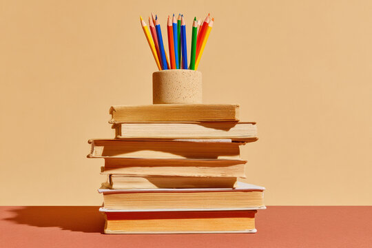 Stack of vintage books with a colorful pencil holder on top for back to school marketing, educational publishing and library banner with copy space