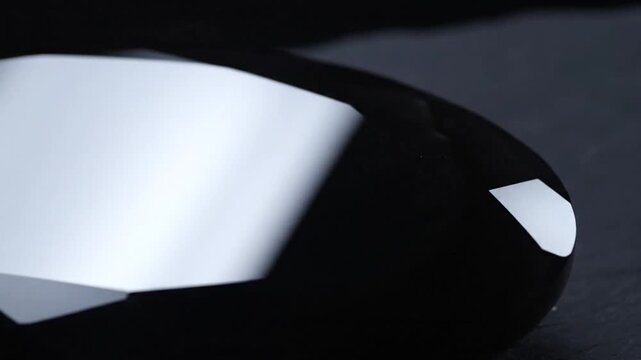 A large, polished black gemstone with many facets reflecting light, symbolizing luxury and value.