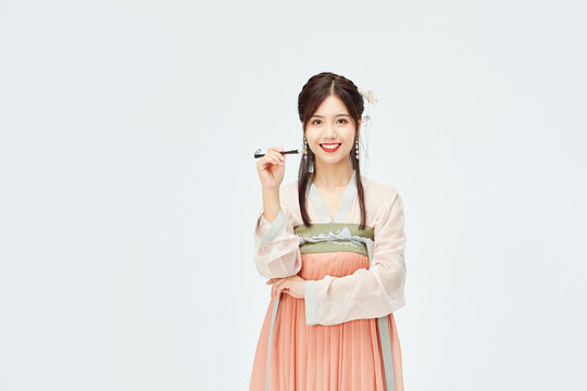 Smiling young Asian woman in traditional hanfu costume holding makeup brush