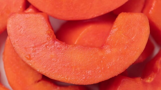 Pile of fresh ripe papaya chunks slowly rotating on a black background. Top view shot