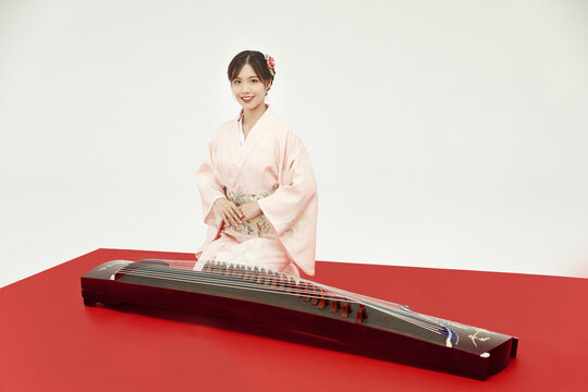 Young woman in kimono with traditional Asian zither