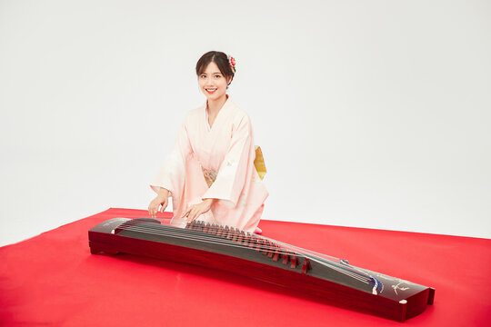 Young woman in kimono playing traditional zither