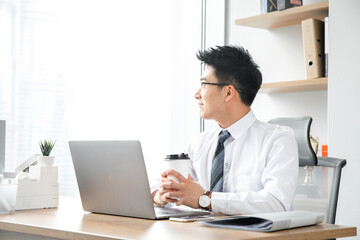 Fototapeta premium Businessman with takeaway coffee taking a work break in a modern office
