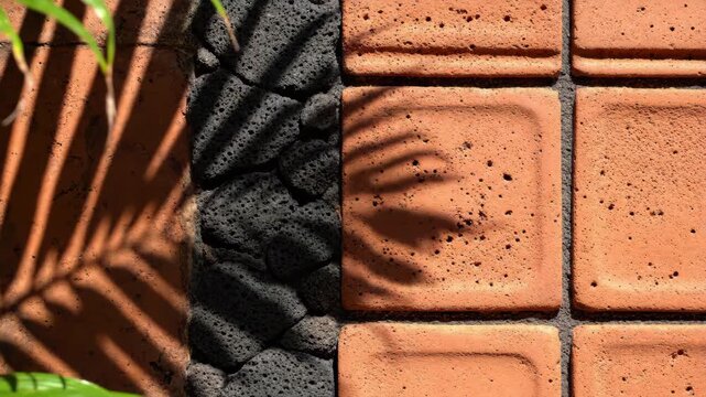Bio based composite tile with natural stone and shadow of palm leaf creating warm textured surface and calm mood in sunlight