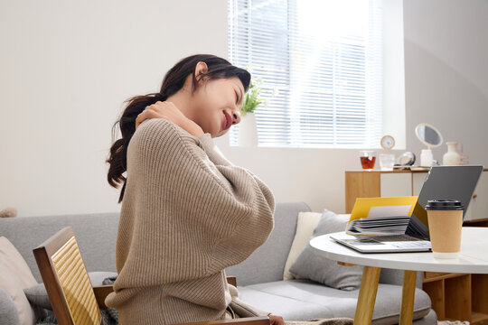 Young woman relieving neck pain during work break at home office