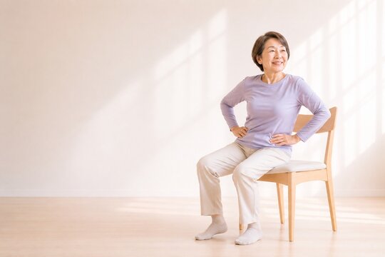 Senior Japanese woman doing pelvic exercise while seated, wide shot