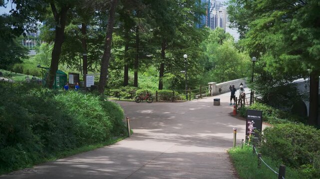 Peaceful afternoon landscape in Seoul Olympic Park, South Korea, featuring a lush green walking path and a bridge