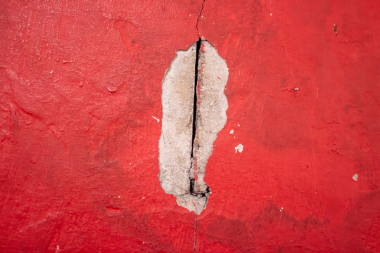 Cracked Red Painted Wall Texture with Exposed Concrete Background