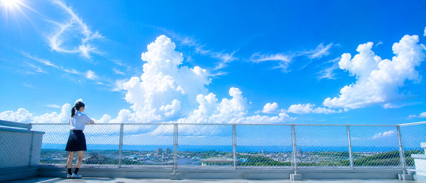 学校の屋上から夏空と入道雲を眺める女子生徒の後ろ姿