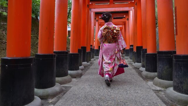 Asian woman in traditional Japanese kimono at Fushimi Inari Shrine in Kyoto Japan.