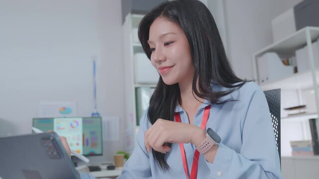 Smiling asian business woman using tablet laptop with equipment placed for doing finance on an home office desk, tax, report, accounting, statistics, and analytical research concept.
