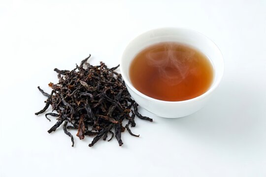 Dried black tea leaves and a Chinese teacup on a white background