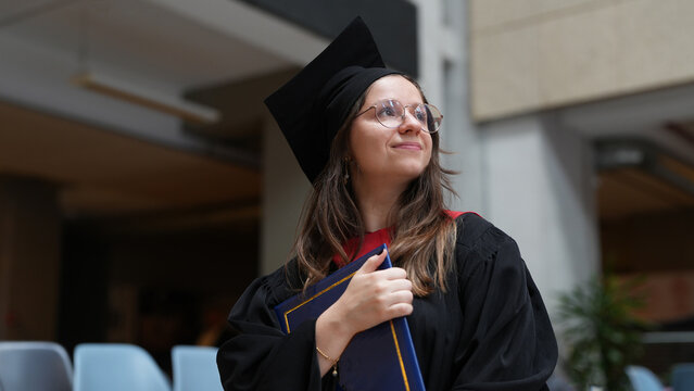 young female graduate with diploma looking up smiling, bright future, higher education