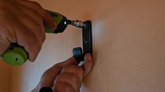Installing a hook on a wall using a drill and screwdriver for home organization and storage