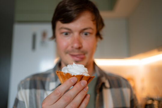 Man excitedly looking at a cupcake, showing strong sugar craving and a sweet tooth while licking lips, representing issues with diet and uncontrolled hunger