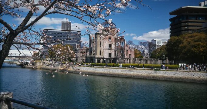Slow Motion Tracking Shot Of Hiroshima Peace Memorial Dome Near River With View of Cherry Blossoms