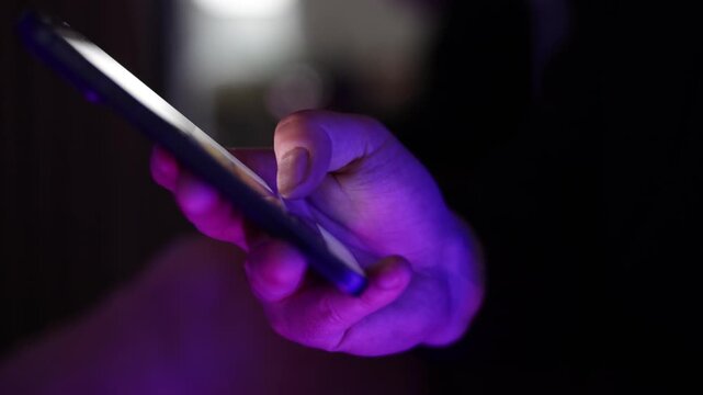 Close-up footage of a person holding a smartphone and scrolling through content on a mobile device.
