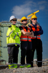 Fototapeta premium Construction worker hard hat safety vest high visibility industrial site teamwork engineer protective eyewear during inspection at refinery with crane, confident stance under blue sky