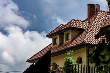 Fototapeta premium Traditional tiled roof and dormer windows against a cloudy blue sky