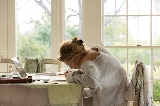 young woman artist doing watercolor drawing in her studio