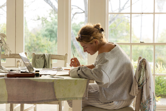 young woman artist doing watercolor drawing in her studio