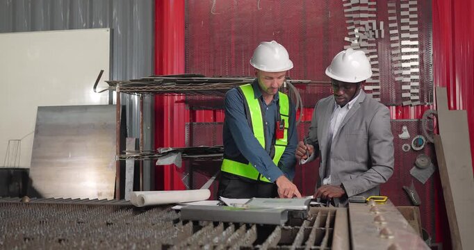 Sales engineer and client confirm a business agreement in an industrial workshop, shaking hands and reviewing contract documents for a custom manufacturing project.
