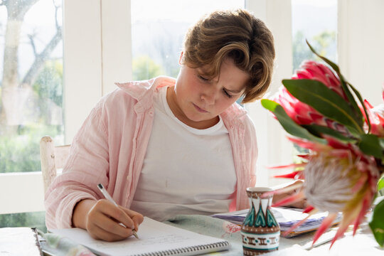 pre teen boy sitting at table doing homework