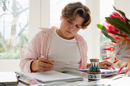 pre teen boy sitting at table doing homework