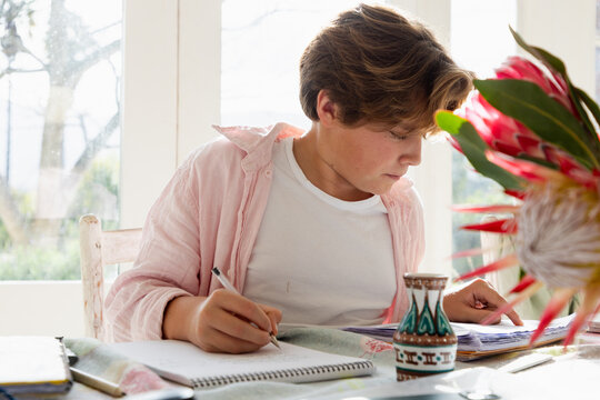 pre teen boy sitting at table doing homework