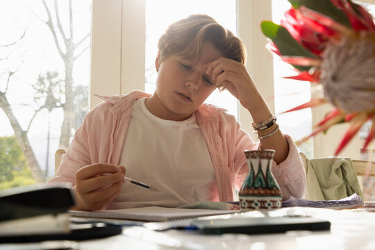 pre teen boy sitting at table doing homework