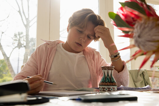 pre teen boy sitting at table doing homework