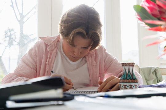 pre teen boy sitting at table doing homework