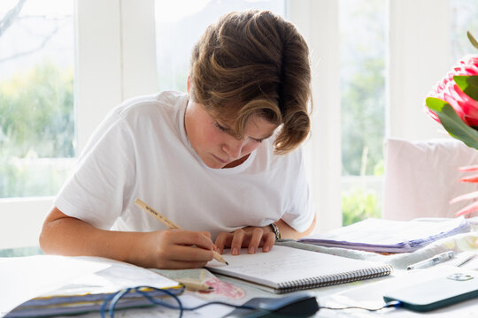 pre teen boy sitting at table doing homework