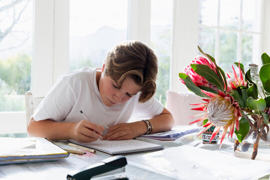 pre teen boy sitting at table doing homework