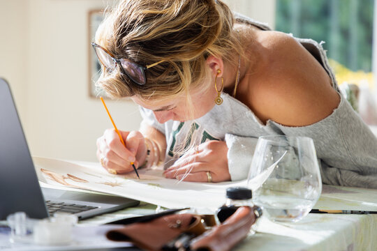 young woman artist working on a watercolor drawing in her studio