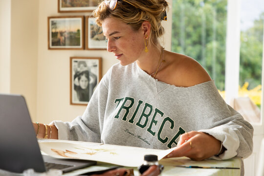 young woman artist working on a watercolor drawing in her studio