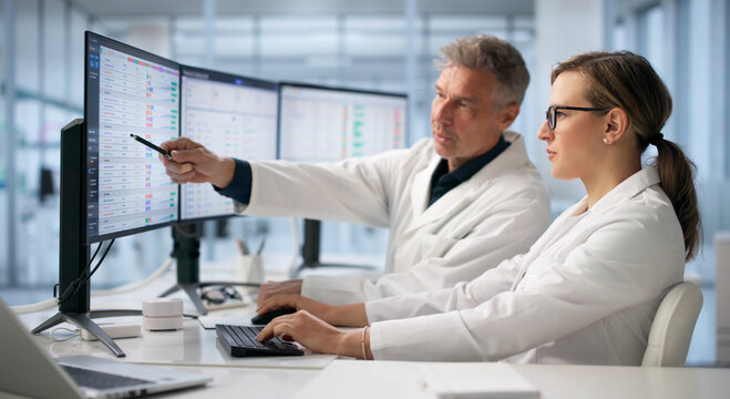 Two Healthcare Analysts Work Together Reviewing Medical Billing Codes