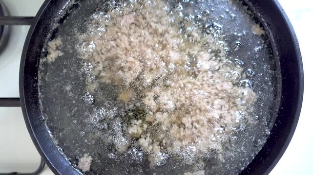 Rendering animal fat in a black frying pan. Carnivore, keto, and paleo diet concept. Healthy animal fats for traditional cooking. Top view close up of melting lard