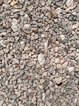 Surface texture of coarse greyish small crushed stones split as aggregate material for construction cast concrete mixture.