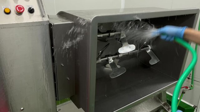 Industrial food mixer being cleaned with water after production. Sanitation procedure supporting food safety, hygiene standards, equipment cleanliness, and food manufacturing operations.