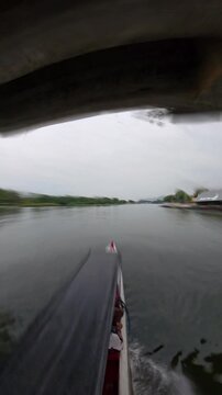 Timelapse from driving plate of a longtail boat navigating the River Kwai towards the General Prem Tinsulanonda Bridge and River Kwai Bridge, showcasing travel and tourism in Kanchanaburi Province
