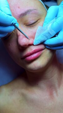 A technician applies a treatment to a client's face in a beauty salon. The procedure includes using tools and wipes for skin care during the day.