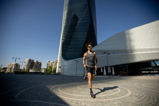 Runner glides through modern cityscape under a clear blue sky