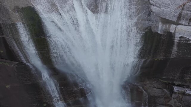 Tilt down on steep, powerful waterfall into natural rock pool - Senpiro Falls - Yakushima, Japan