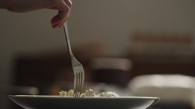 Close low angle plate of penne pasta with herb garnish and warm rim lighting