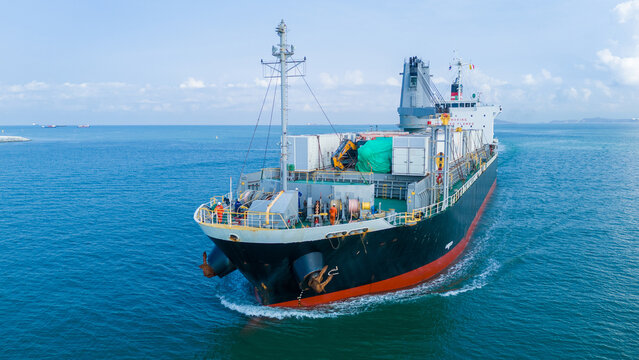 argo ship navigating through the deep blue ocean, carrying heavy equipment and containers on deck, representing global maritime logistics and international trade.