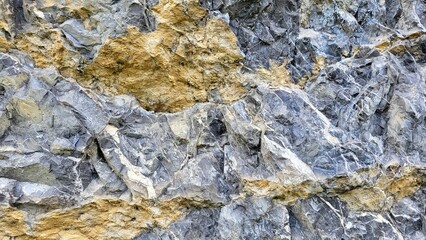 Fototapeta premium Detailed close-up of a distinctive rock formation featuring various shades of gray and warm sandstone colors. The image highlights natural textures and geological patterns.